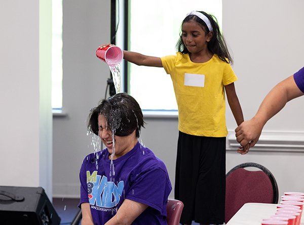 Girl pouring water on boy's head